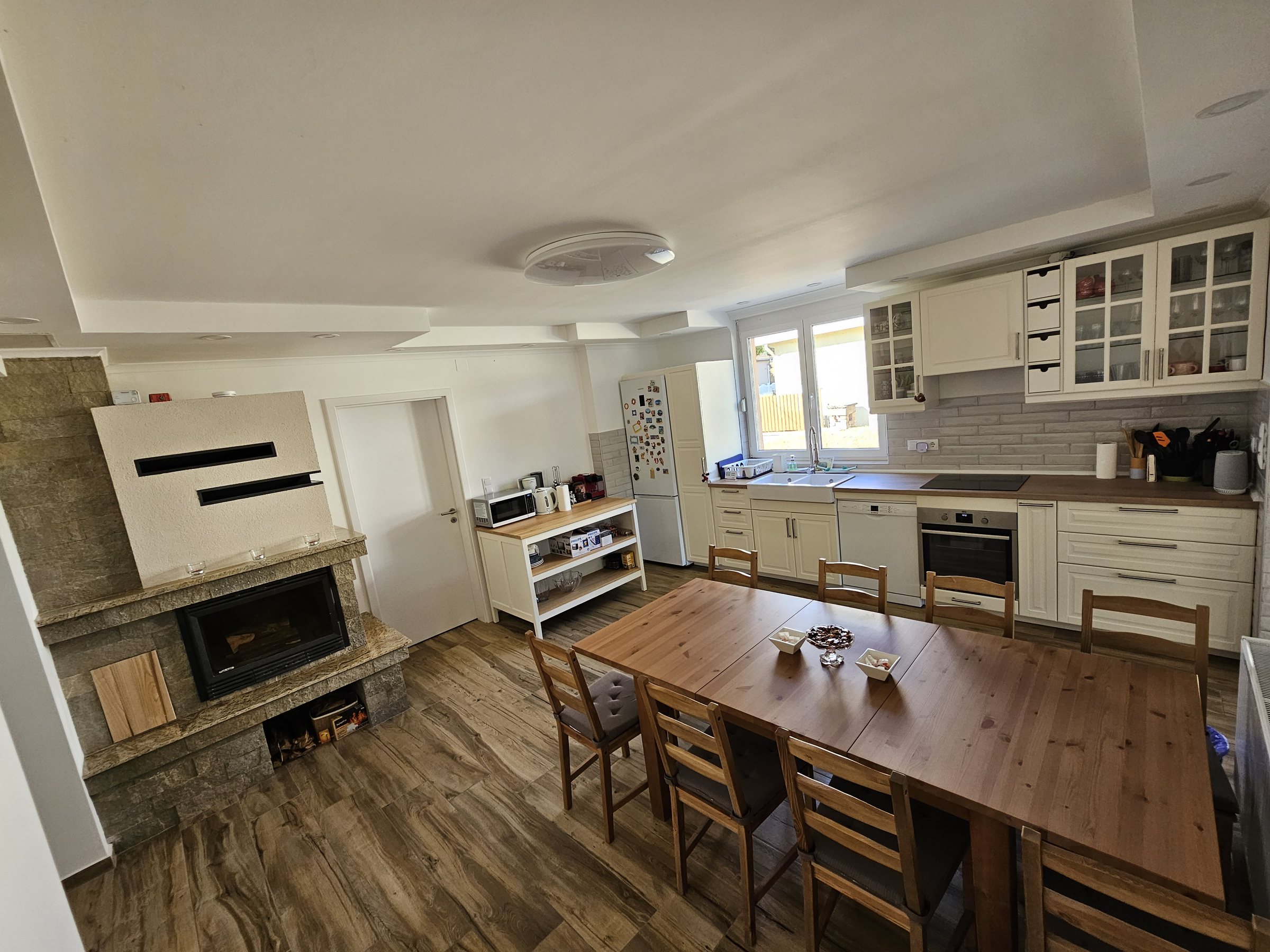 Bright open kitchen, dining area and fireplace at Mökki